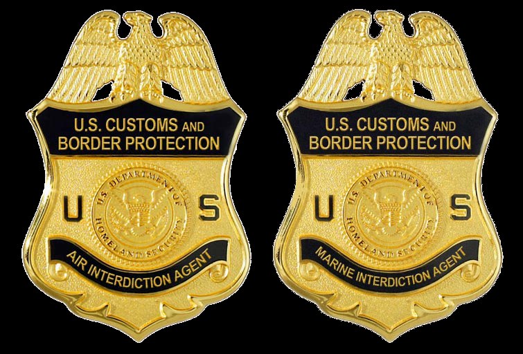 Zwei goldfarbene Abzeichen mit der Aufschrift "U.S. Customs and Border Protection" auf einem weißen Hintergrund.