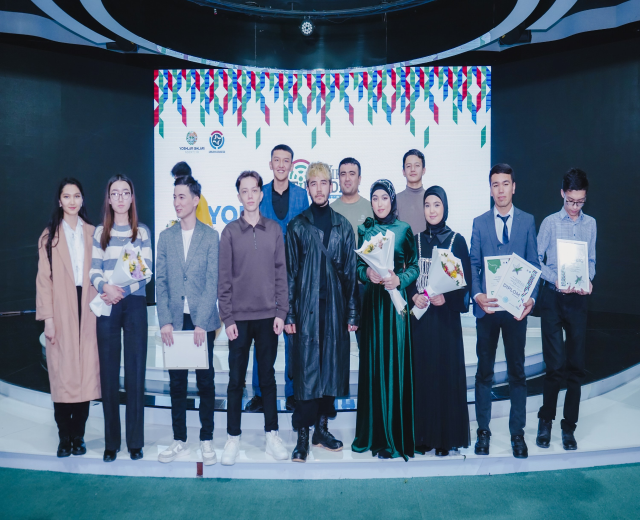 Gruppe von Menschen auf einer Bühne mit Blumensträußen und Urkunden, im Hintergrund ein "Jugend-Solar-Awards 2019"-Plakat