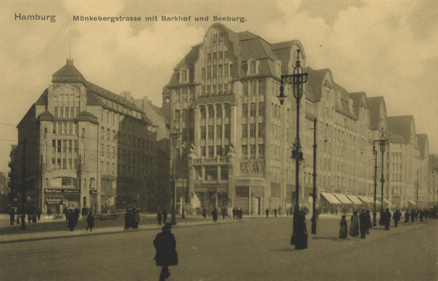 Schwarzes und weißes Foto von Fußgängern, die auf einer Straße in Hamburg, Deutschland, entlanggehen, gesäumt von Gebäuden, Straßenlaternen, Straßenlaternen und Fahrzeugen unter einem bewölkten Himmel.