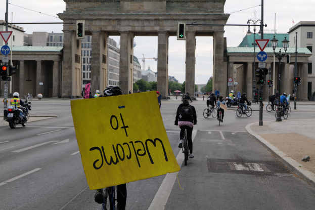Gruppe von Radfahrern fährt vor dem Brandenburger Tor in Berlin, Deutschland, mit einem gelben Schild.