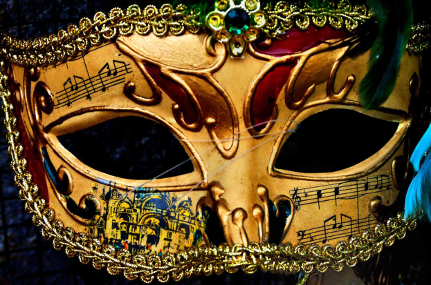 Ein Nahaufnahme eines Karnevals-Masken mit detaillierten Designs, Federn und Noten, mit einem unscharfen Hintergrund.