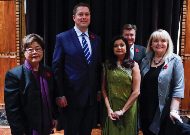Gruppe von Menschen vor einem schwarzen Vorhang mit einer hölzernen Wand im Hintergrund, die scheinbar Mitglieder der Freien Demokratischen Partei auf einer Versammlung sind.