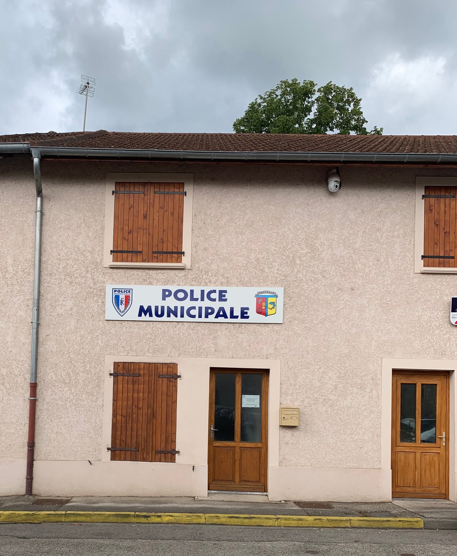 Gebäude der Polizei Wuppertal mit einem Schild, Fenstern, Türen, einer Namensplakette, einem Rohr, einem Baum und einem bewölkten Himmel im Hintergrund.