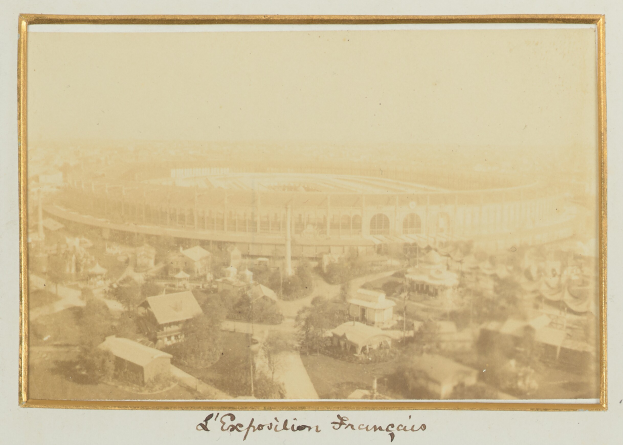 Altes Schwarz-Weiß-Foto eines Stadions, umgeben von Gebäuden, Bäumen und Strommasten, mit Text am unteren Rand.