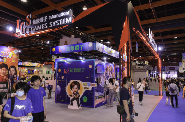 Eine Gruppe von Menschen, die durch einen Convention Hall auf einer Gaming Expo in China gehen, einige tragen Taschen und halten Gegenstände, mit Display-Boards, Deckenbeleuchtung und einem Teppichboden.