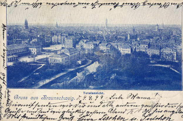 Alte Postkarte zeigt eine Stadtansicht von einem Hügel aus, mit Gebäuden, Bäumen und handgeschriebener Text.