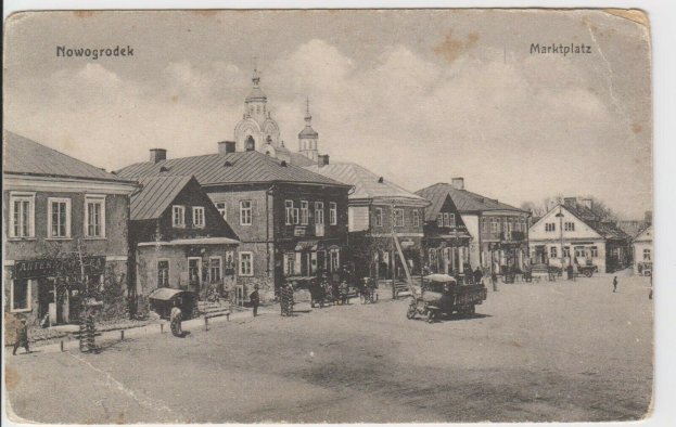 Schwarz-weiß-Foto vom Marktplatz in Nowogrodziec, Deutschland mit Gebäuden, Menschen, Karren, Pfählen, Bäumen und Himmel, beschriftet mit "Marktplatz in Nowogrodeek, Deutschland".