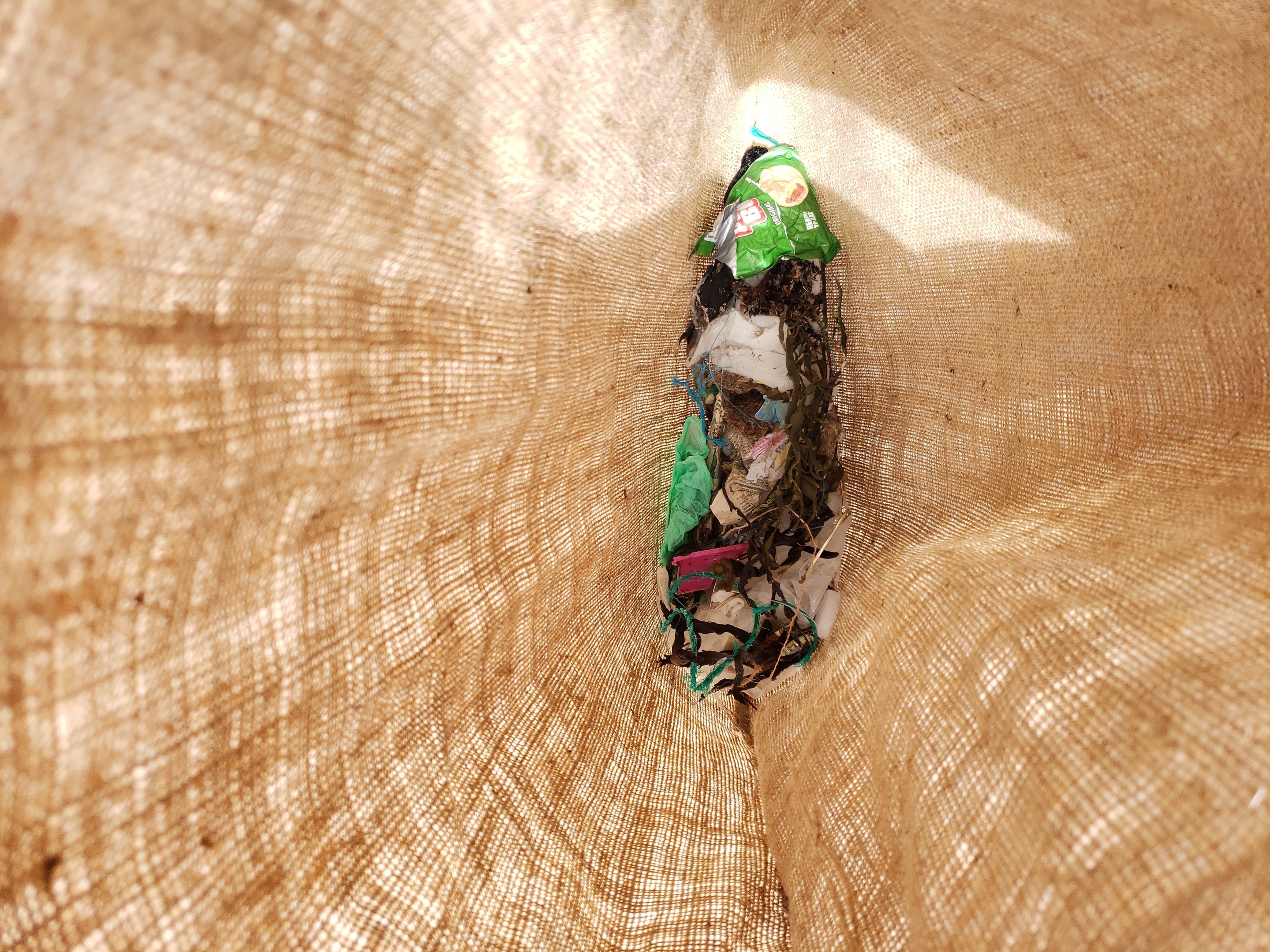 Nahaufnahme eines Stücks recycelten Papiers auf einem Tisch mit einem Jutestoff-Hintergrund.