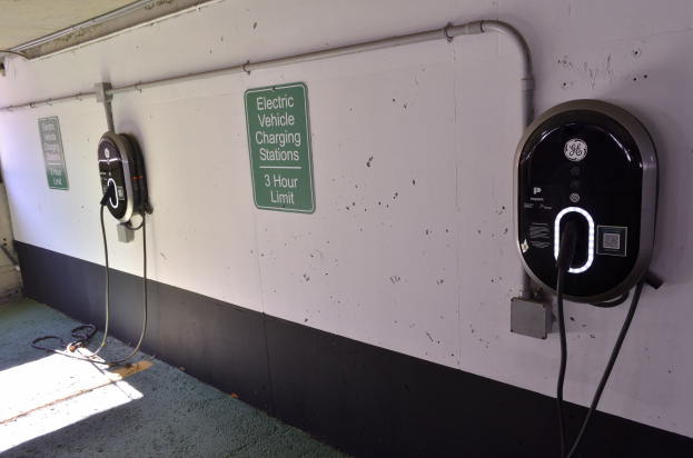 Elektrische Fahrzeug-Ladestationen an einer Wand in einer Tiefgarage mit Informationsschildern darunter.