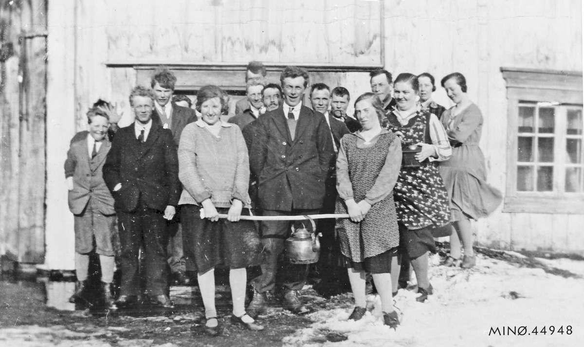 Schwarzes und weißes Foto von Menschen, die ein Band vor einem Gebäude mit einem Fenster und einer Tür halten und bei einer Schul-Eröffnungsfeier lächeln.