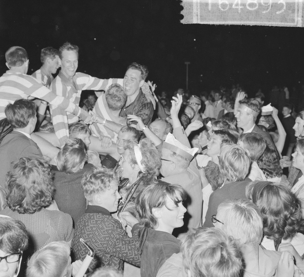 Schwarzes und weißes Foto einer Menge bei einem Konzert mit einer Gruppe von Menschen in der Mitte und Text in der oberen rechten Ecke.