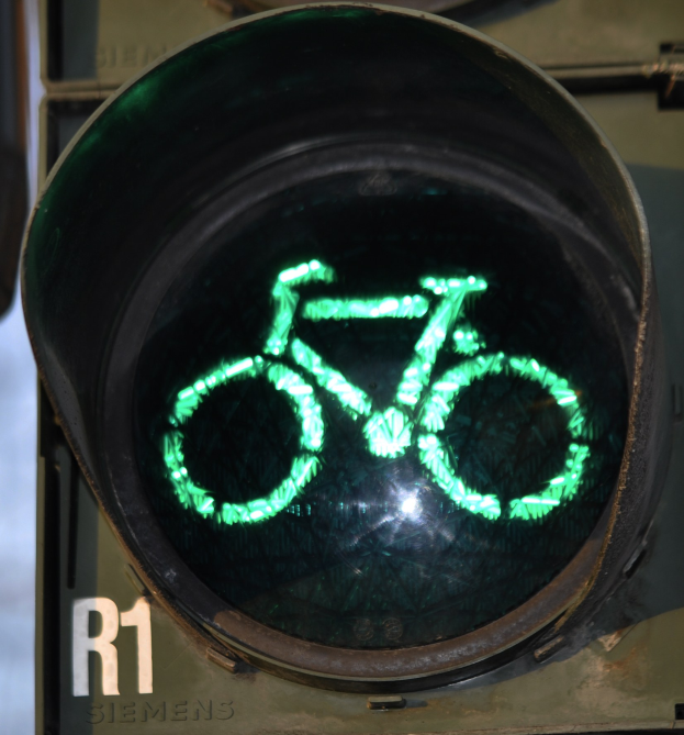 Grüne Ampel mit Fahrradsymbol, das vor einer Wand leuchtet.