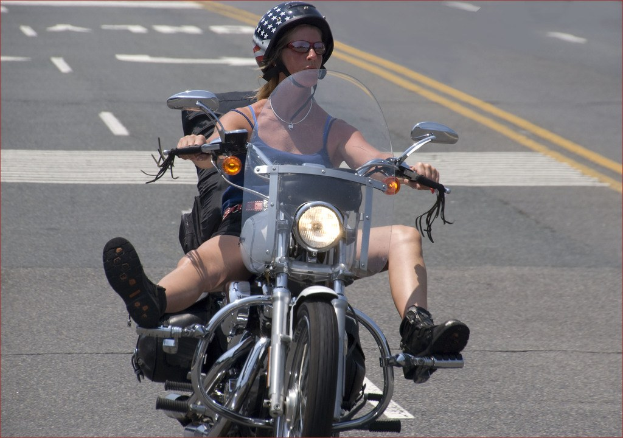 Eine Frau mit einem schwarzen Helm fährt ein Fahrrad auf einer Straße.