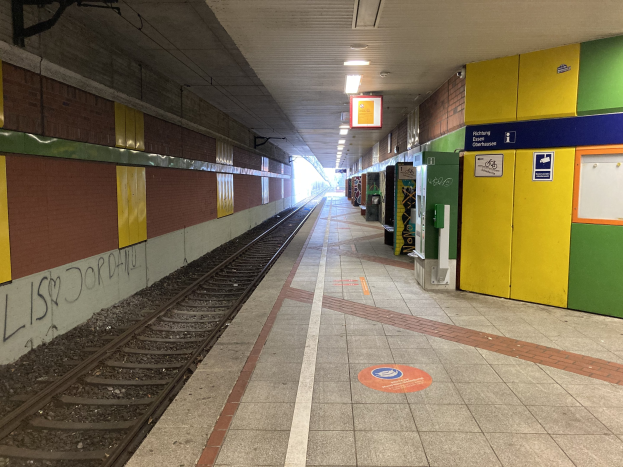 Ein Bahnsteig mit einem Zug auf den Schienen, beleuchtet von Deckenlampen, mit Graffiti an einer linken Wand und ein paar Gegenständen auf der rechten Seite, identifiziert als Berliner Hauptbahnhof in Berlin, Deutschland.