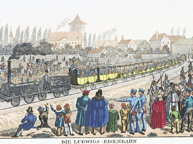 Eine Gruppe von Menschen, die um einen Zug auf einem Gleis stehen, mit einigen im Zug und anderen auf dem Boden, in der Nähe von Gebäuden und Bäumen, mit dem Text "Ludwigs-Eisenbahn, der erste Bahnhof in Deutschland" unten.