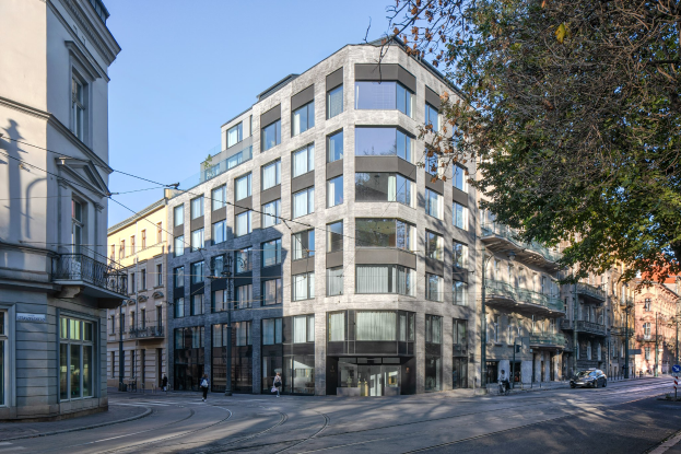 Großes Bürogebäude mit vielen Fenstern, umgeben von Straßeninfrastruktur, Fahrzeugen, Fußgängern, Bäumen und einem bewölkten Himmel, identifiziert als neuer Firmensitz.