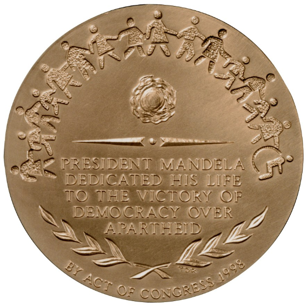 Goldene Medaille mit der Inschrift "Präsident Mandela widmete sein Leben dem Sieg der Demokratie über die Apartheid" auf einem weißen Hintergrund.
