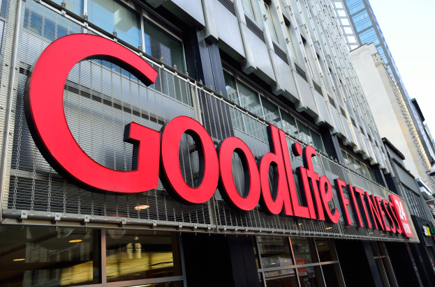 Ein Goodlife Fitness-Studio in New York City mit Glaswänden und einem Namensschild, neben anderen Gebäuden unter einem sichtbaren Himmel.